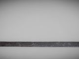 a close up of an old metal ruler on a white surface