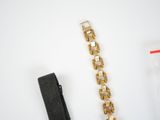 a black strap and a gold watch on a white table