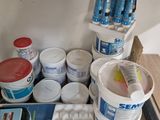 many buckets of paint sitting on a shelf