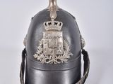 un vieux casque surmonté d'une couronne, posé sur une surface blanche