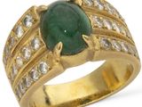 a close up of a ring with a green stone surrounded by diamonds