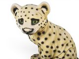 a figurine of a cheetah sitting on a white surface