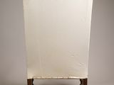 the back of a white chair with wood legs and a white cushion