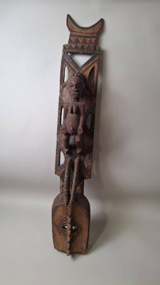 une vieille sculpture en bois représentant un homme assis sur un bloc de bois