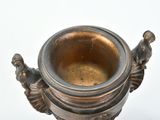 a metal cup with a handle on a white surface