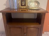 a small wooden cabinet with a silver vase on top of it