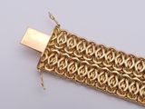 an image of a close up of a gold bracelet on a white surface
