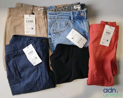 quatre paires de pantalons pour homme, encore étiquetés, posées sur une table