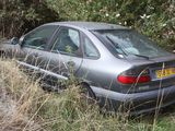 a car that is sitting in the grass by the trees