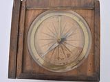 a small wooden clock with a compass on it