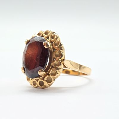 Gros plan sur une bague en or ornée d'une pierre rouge