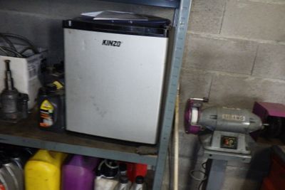 un petit réfrigérateur posé sur une étagère dans un garage