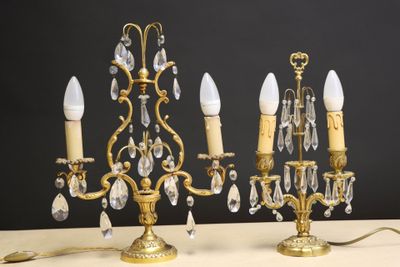 une paire de chandeliers anciens en laiton et cristal posés sur une table