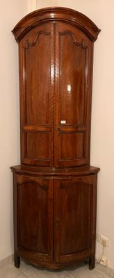 une armoire d'angle placée dans un coin de la pièce