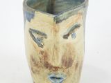 a close up of a vase with a face on it