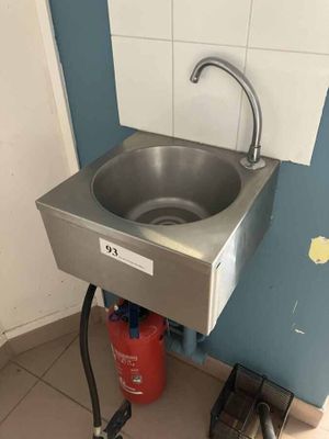 a sink in the corner of a bathroom with a hose attached to it