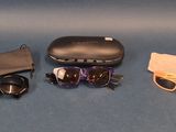 une paire de lunettes de soleil, un étui et une paire de lunettes posés sur une surface bleue