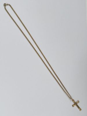 Gros plan sur un collier en or orné d'une croix