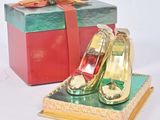 une petite boîte sur laquelle est posée une paire de chaussures dorées