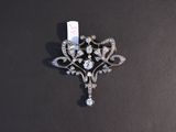 an antique diamond broochle on a black surface with a tag