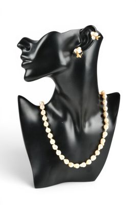une tête de mannequin noire ornée de perles et de boucles d'oreilles en or