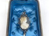 une boîte en velours bleu contenant une broche en argent