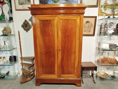 a wooden cabinet with glass shelves and pictures on the wall