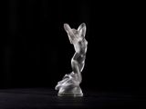 a glass sculpture of a man on a black surface