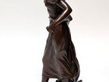 bronze statue of a woman holding a bird on a rock