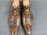 pair of brown leather shoes with laces on them on a gray surface