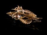 an image of a gold brooch with pearls on a black surface