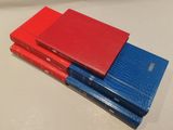 three red and blue books stacked on top of each other on a table