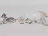 two figurines of animals sitting on a white surface
