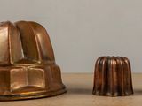 two metal molds sitting on a table next to each other