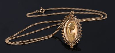 a close up of a gold necklace with a picture of a woman on it
