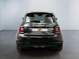 the back end of a silver car in a room with a white wall