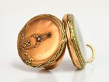 a close up of a gold pocket watch on a white surface