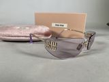 purple sunglasses with gold details and a pink case on a table