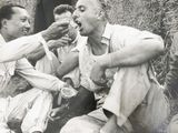 trois hommes assis par terre en train de manger ensemble