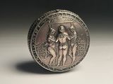 an old silver coin sitting on top of a table next to a black background