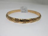 gros plan d'un bracelet en or sur une surface blanche