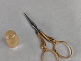 a pair of scissors next to a thimble on a table