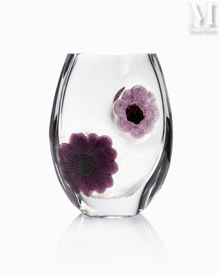 un vase en verre contenant des fleurs violettes, posé sur une surface blanche