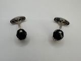 une paire de boutons de manchette noirs et blancs posés sur une surface blanche