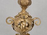 a gold vase with a bird on top of it