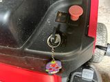 a red moped parked in a garage with a keychain attached to it
