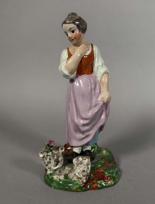 une figurine représentant une femme debout sur un rocher avec un chien