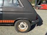 a black car with orange stripes parked in a parking lot