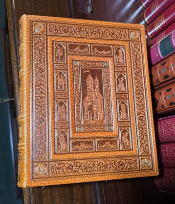 un vieux livre posé sur une étagère en bois, à côté d'une pile de livres