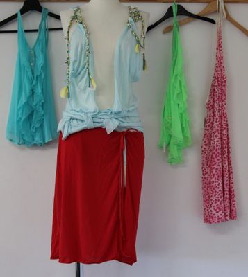 three dresses hanging on a clothes rack in front of a white wall